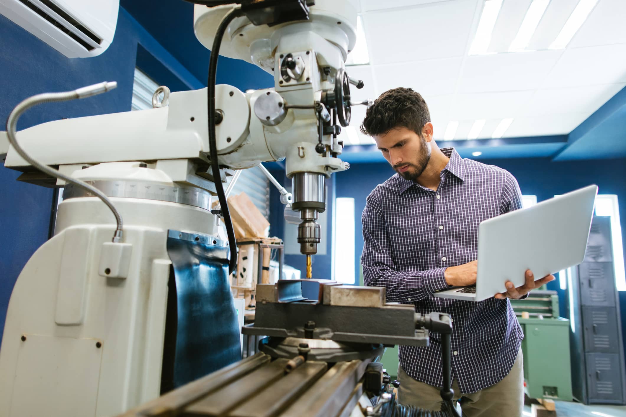 Cytotechnologist holds laptop in hand while looking at lab equipment