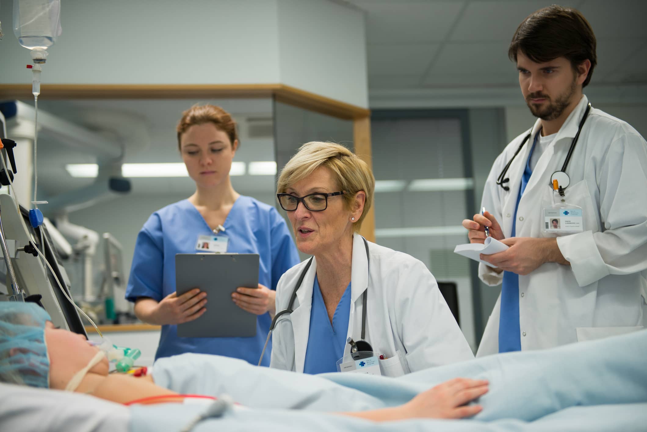 Two physician assistants take notes while pathology physician speaks to patient